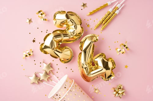 Visualização: Uma exibição vibrante de balões numéricos dourados e decorações de festa em um fundo rosa