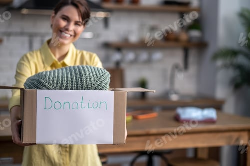 Preview: Smiling female volunteer showing things prepared for donation