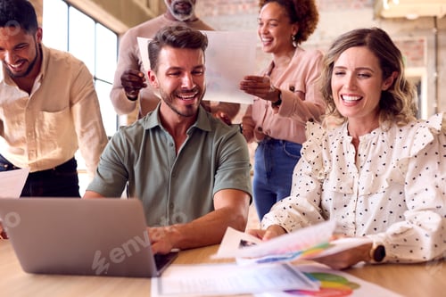 Preview: Multi-Cultural Business Team Meeting Around Laptop In Busy Office