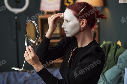 Preview: Caucasian Gen Z Woman Applying Face Paint While Sitting Indoors