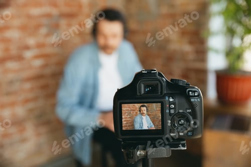 Preview: Caucasian musician playing hand drum during online concert at home isolated and quarantined, focus