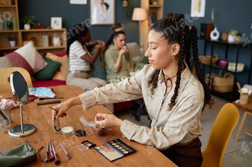 Preview: Multicultural Woman Applying Makeup at Table with Friends Talking