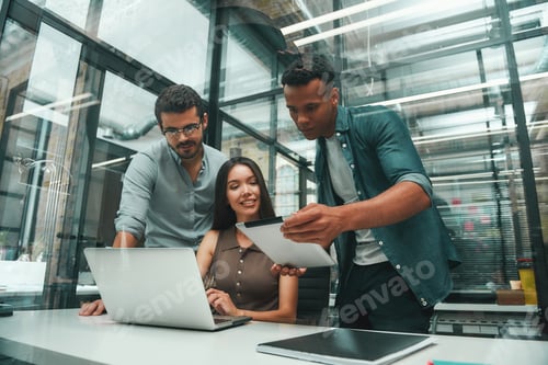 Preview: Searching for solutions. Group of three young and positive employees using modern technologies and