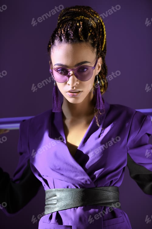 Preview: Stylish girl posing in ultra violet jacket and sunglasses, isolated on purple