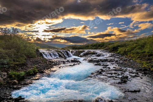 Preview: Bruarfoss Waterfall landscape with clear blue water at sunset.