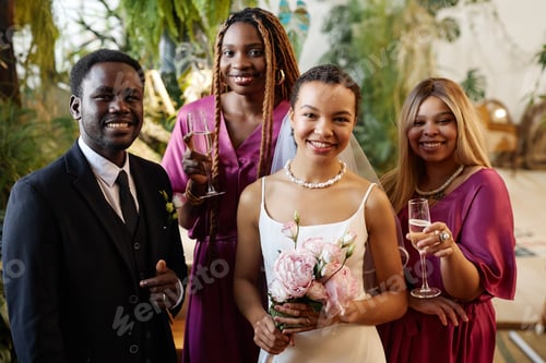 Preview: Young African American couple as bride and groom posing with bridesmaids