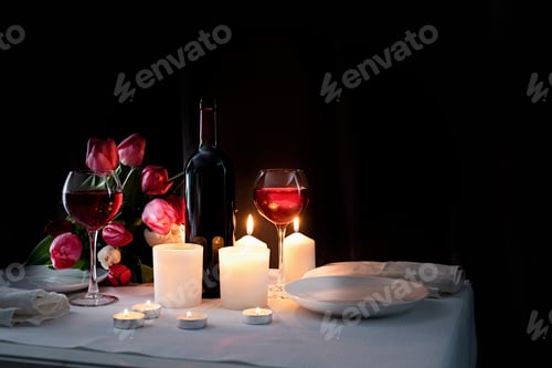 Preview: Romantic dinner table setting with burning candles, wine and tulips