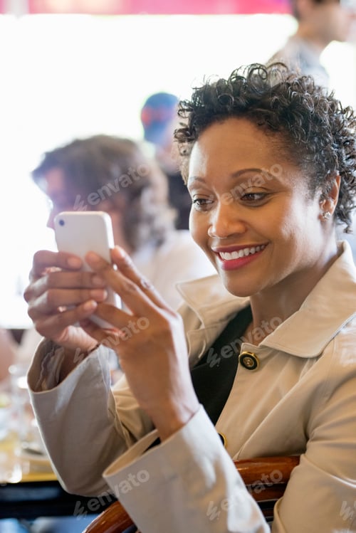 Preview: A group of people sitting in a cafe around a table. Men and women checking their smart phones.
