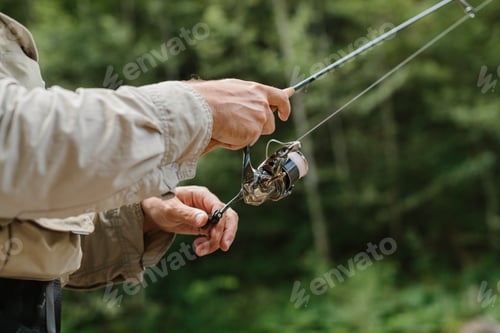 Preview: Fisherman reeling line on spinning reel in river