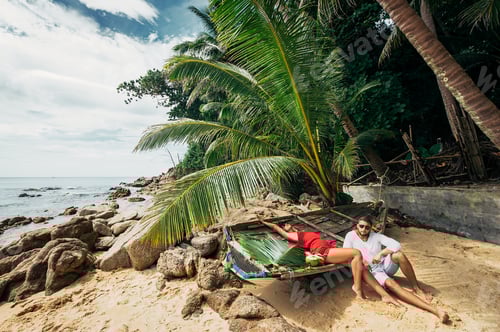 Preview: Couple on the shore of Paradise island. Couple in love on the seaside drinking coconut