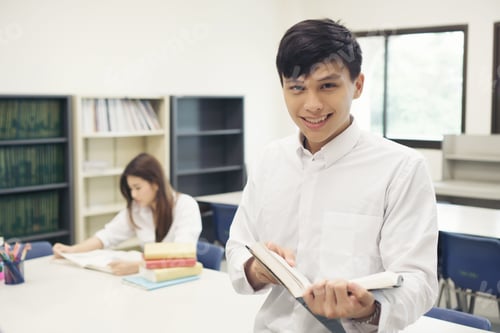 Preview: Young student reading book in library . Education concept.