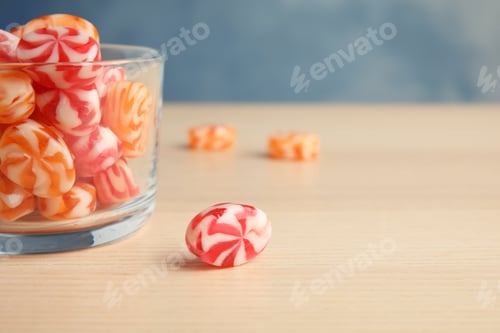 Preview: Glass with delicious colorful candies on wooden table. Space for text