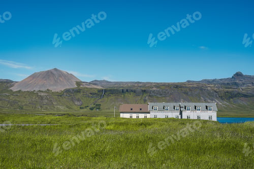 Preview: Scandinavian house on meadow and volcanic mountain background at Iceland