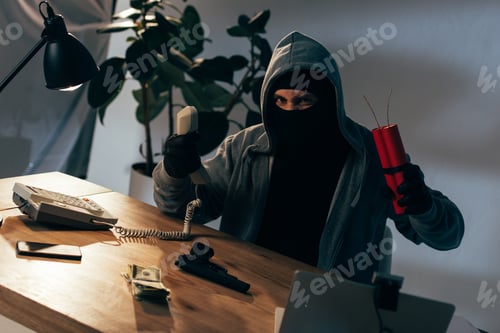 Preview: Angry terrorist in mask and gloves holding handset and dynamite