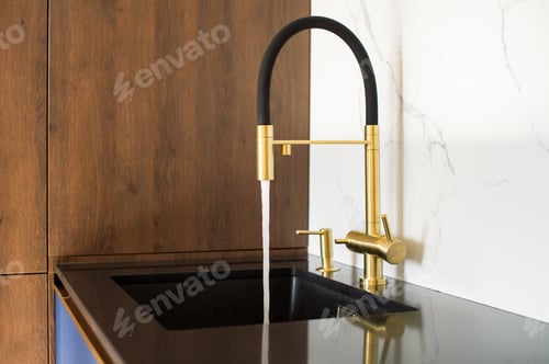 Preview: Water pours from a kitchen faucet with a silicone spout in the kitchen. Black tabletop
