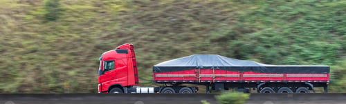 Preview: Panoramic shot of a red truck driving on the road