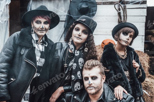 Preview: Scary family, mother, father, daughters celebrating halloween. Terrifying black skull half-face make