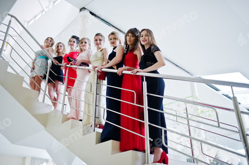 Preview: Group of outstandingly beautiful ladies in dresses posing on the stairs.