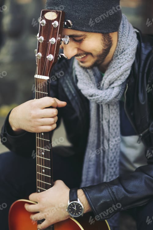 Preview: Young musician with guitar in city