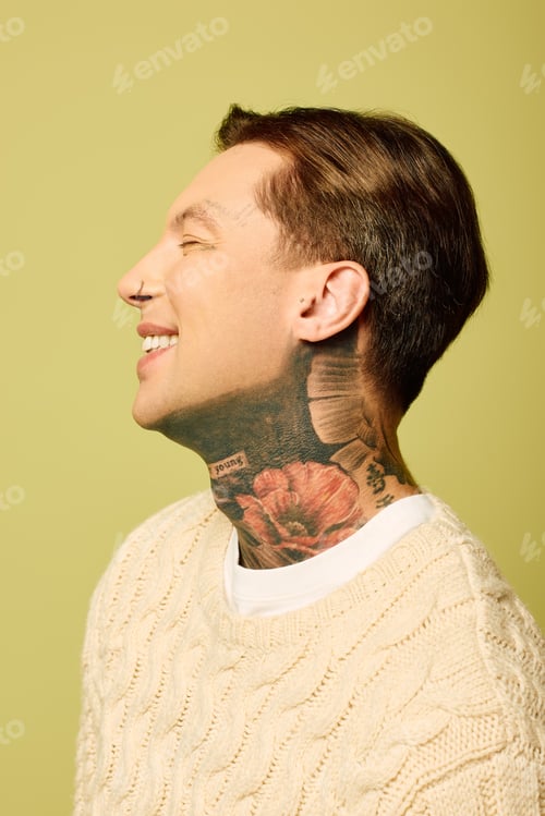 Preview: A young man with intricate tattoos smiles against a bright yellow backdrop