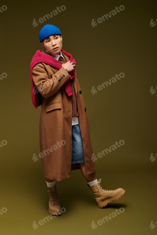 Preview: Stylish young Asian man showcasing contemporary fashion in a dynamic pose against a green backdrop