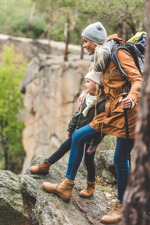 Preview: smiling mother and little daughter trekking together in autumn forest