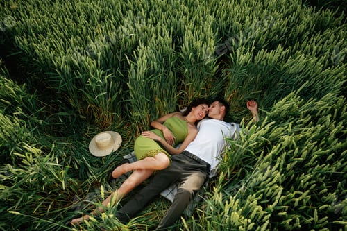 Preview: Couple is lying down on the agricultural field with high wheat that is growing