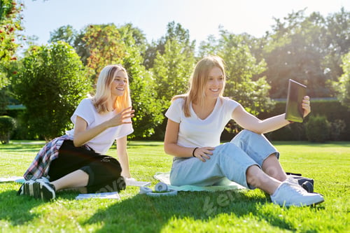 Preview: Two laughing talking female students using digital tablet for video communication