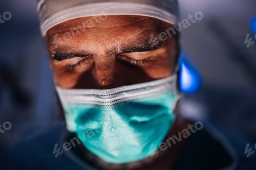 Preview: Intense Surgeon in Blue Scrubs Adjusting Mask Amid Surgery Prep