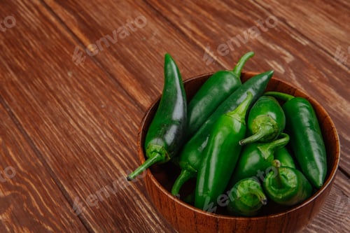Preview: side view of fresh green chili peppers in a wooden bowl on rustic background with copy space