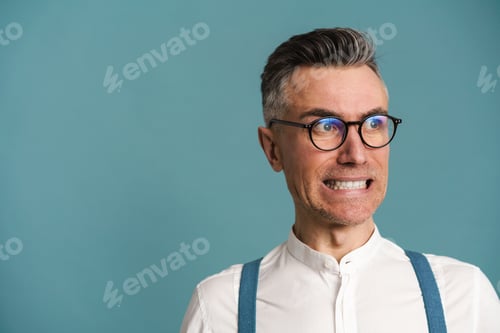 Preview: Displeased grey-haired man in eyeglasses grimacing and looking aside