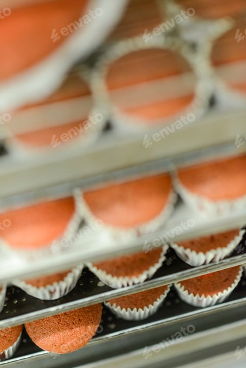 Preview: bakied group of undecorated red velvet cupcakes in bakery in a trolley
