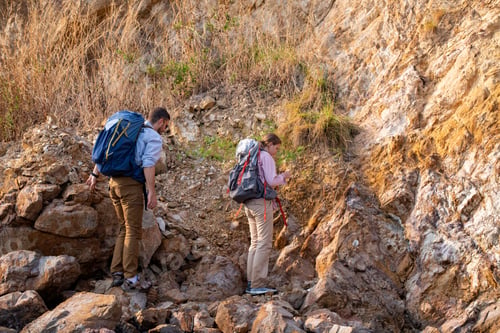 Preview: Tourists show helping young woman with backpacks hike on rocky top mountain trekking and soft foggy
