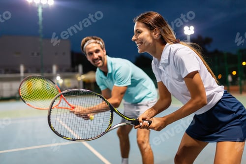 Preview: Young couple on tennis court. Handsome man and attractive woman are playing tennis.