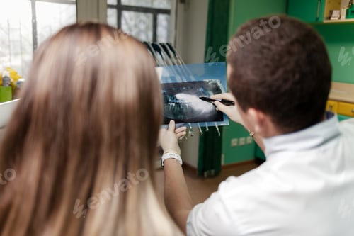 Preview: Dentist doctor shows x-ray image to patient. Dentist and patient discuss x-ray image
