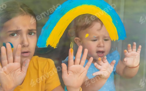 Preview: Children on the window painted a rainbow Ukraine peaceful sky. Selective focus.