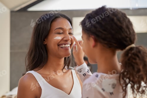 Preview: Child applying cream to mother face during morning routine