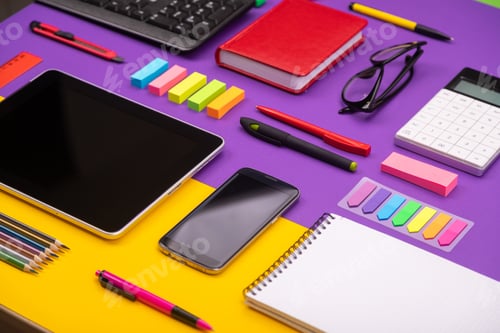 Preview: Modern working place with tablet, calculator, notebook and smartphone on purple and orange