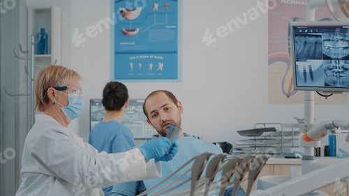 Preview: Senior dentist explaining teeth radiography to patient