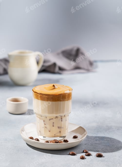 Preview: Dalgona coffee. Whipped instant coffee in a glass with coffee beans on a blue background with shadow