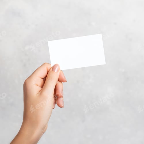 Preview: Female hand holding a blank business card, cutaway on gray concrete background with copy space.