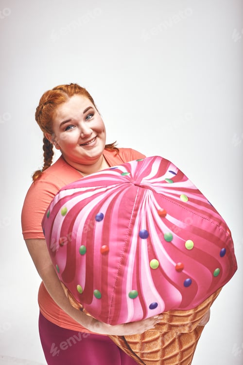 Preview: Red haired, chubby woman is holding a huge ice cream. Close-up