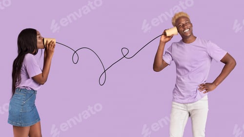 Preview: Handsome black guy taking to his girlfriend on tin can telephone over lilac studio background
