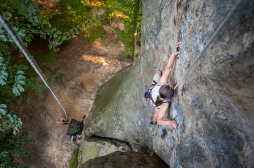 Preview: Woman rock climber is climbing on a rocky wall