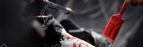 Preview: Header Image of Paintbrush Dripping Drops of Red Paint onto Jacket Coloring Fabrics Indoors