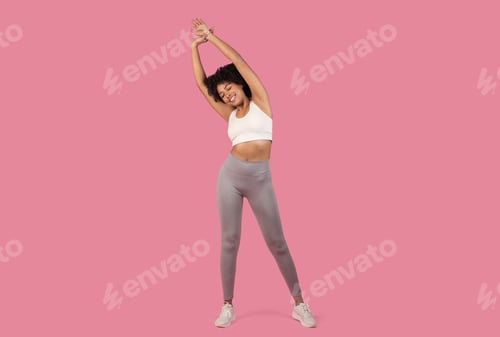 Preview: Sporty woman stretching on a pink background
