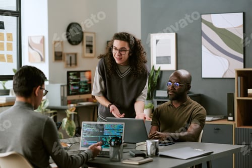 Preview: Young Caucasian Man Explaining Project to Diverse Colleagues in Office