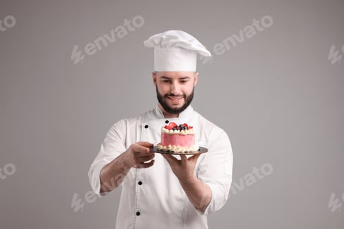 Preview: Happy confectioner in uniform holding delicious cake with berries on light grey background