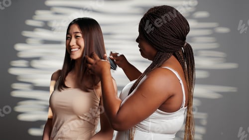 Preview: African american girl brushing hair of asian friend