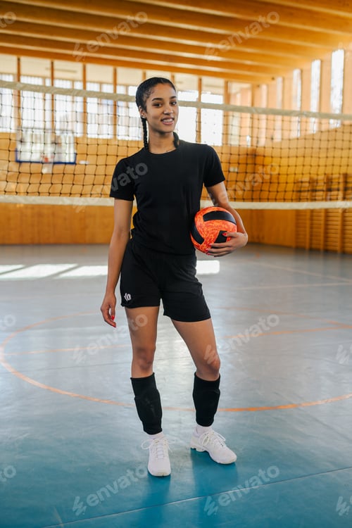 Preview: Interracial teenage volleyball player with ball smiling at the camera.